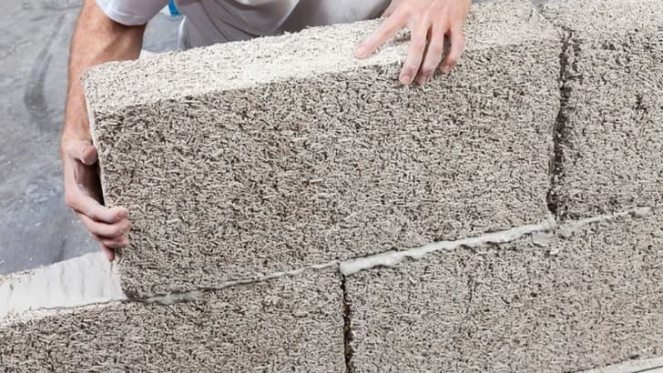 Homme assemblant un mur composé de briques de chanvre