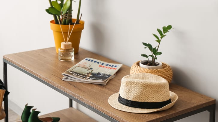 Table d'entrée avec plantes, diffuseur, revues, chapeau et souliers