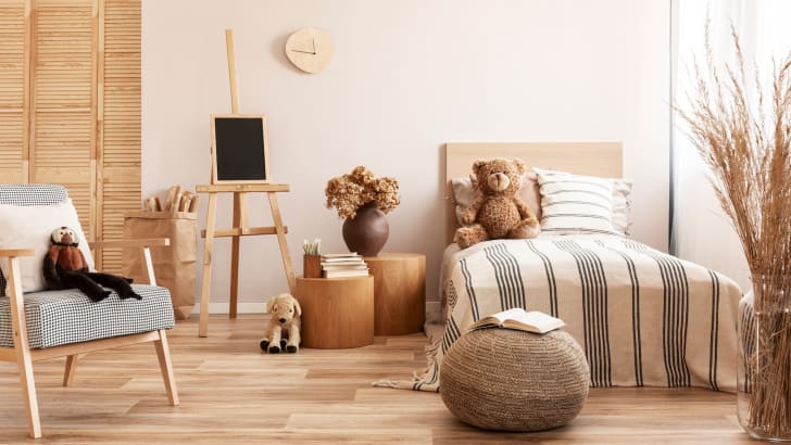 Ourson sur un lit simple en bois dans une chambre d'enfant naturelle avec des accessoires beiges