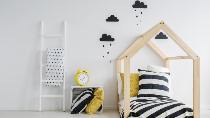 Chambre d'enfant moderne et élégante, découpes adhésives de nuages noirs collés au mur, literie noire et blanche