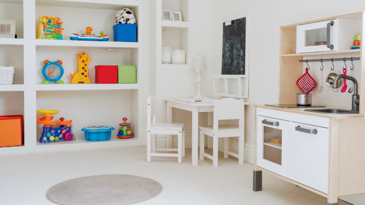 Jouets pour enfants colorés entreposés sur des tablettes dans une pièce aux couleurs neutres