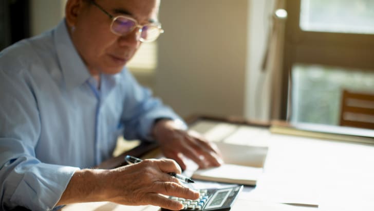 Homme âgé asiatique faisant des calculs