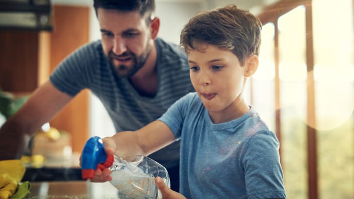 Enfant nettoyant un comptoir sous les yeux de son père