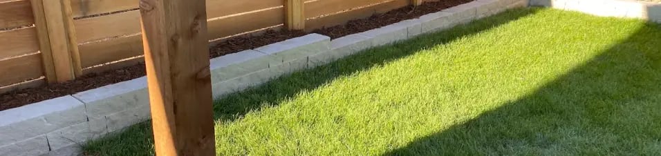 Backyard landscaping with fence, lawn and retaining wall