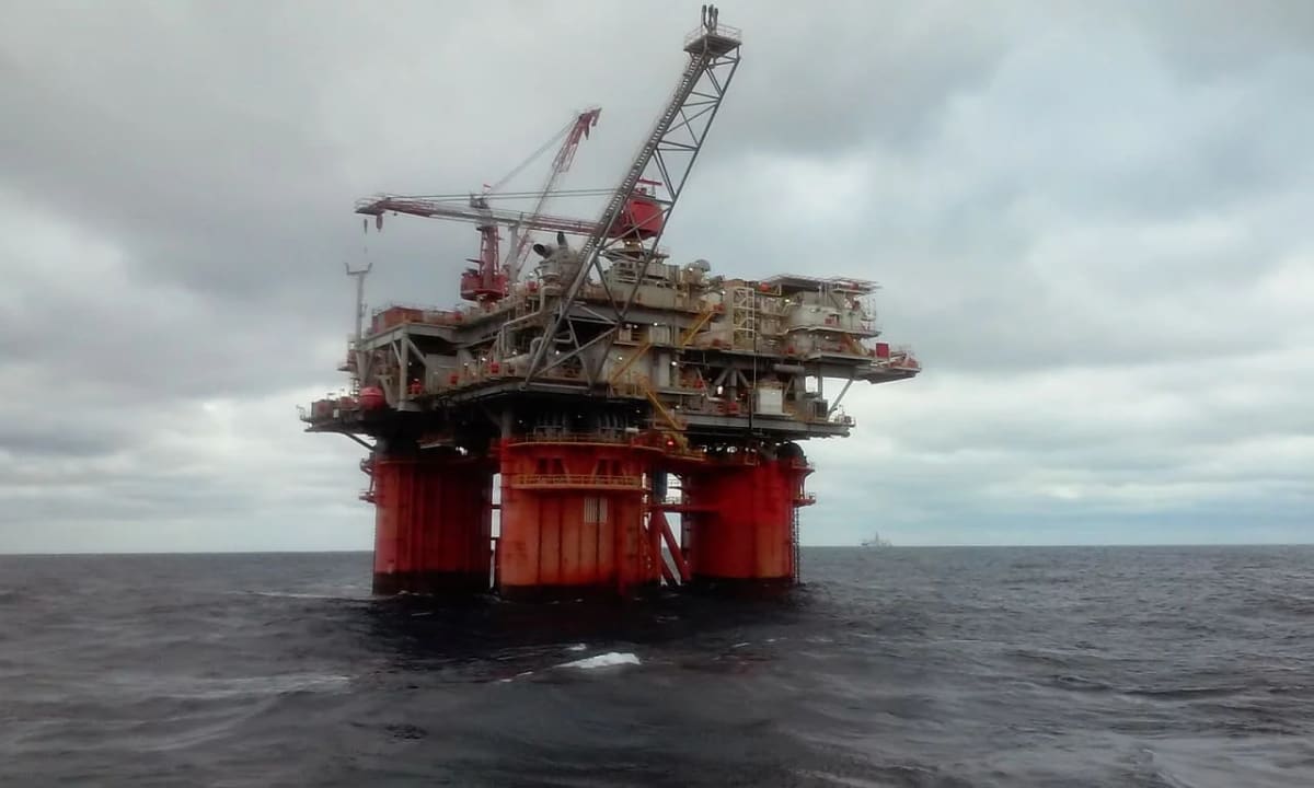 Plataforma petrolera en alta mar, destacando estructuras metálicas sobre un océano bajo un cielo nublado.