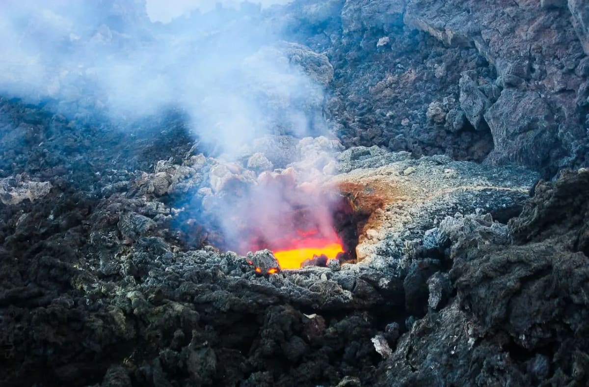 Cráter del volcán Etna con lava incandescente y emisión de gases.