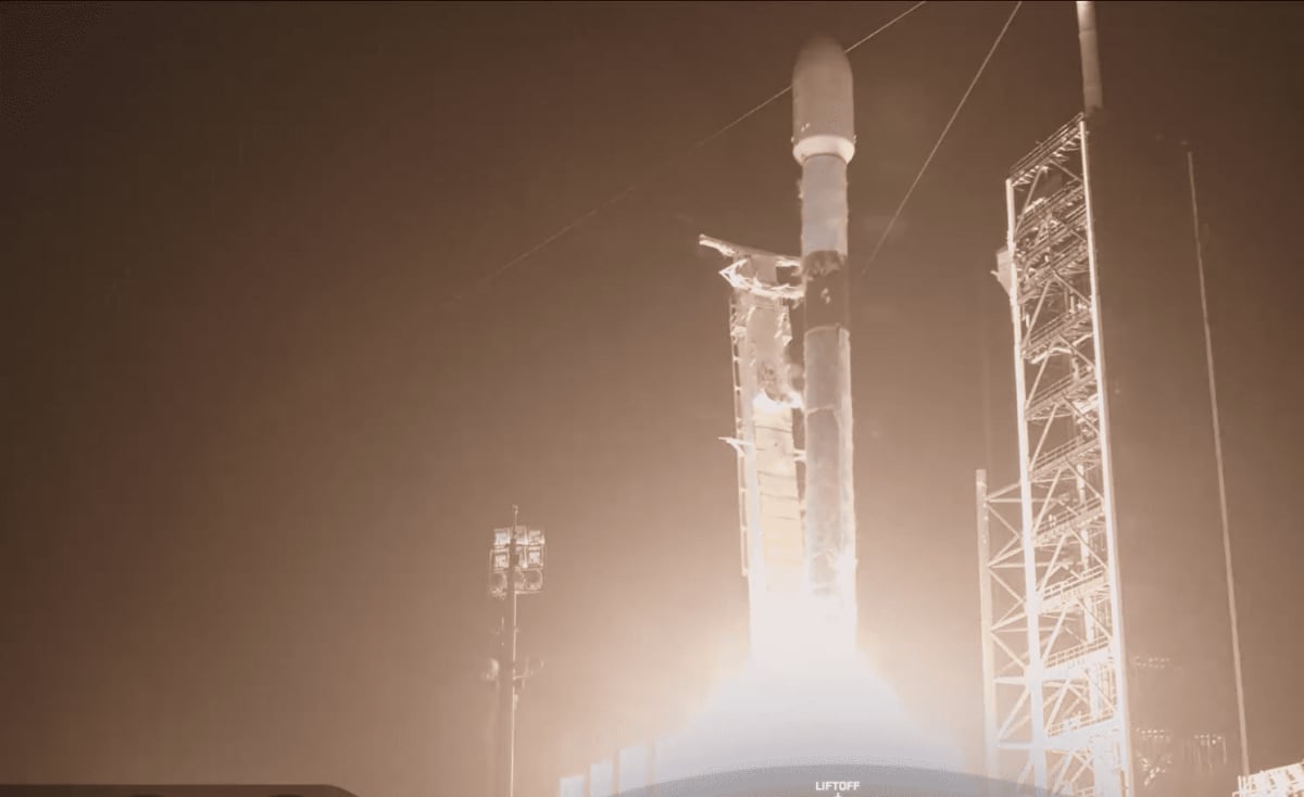 Falcon 9 de SpaceX despegando de una base de lanzamiento en un cielo despejado, con el océano visible en el fondo.