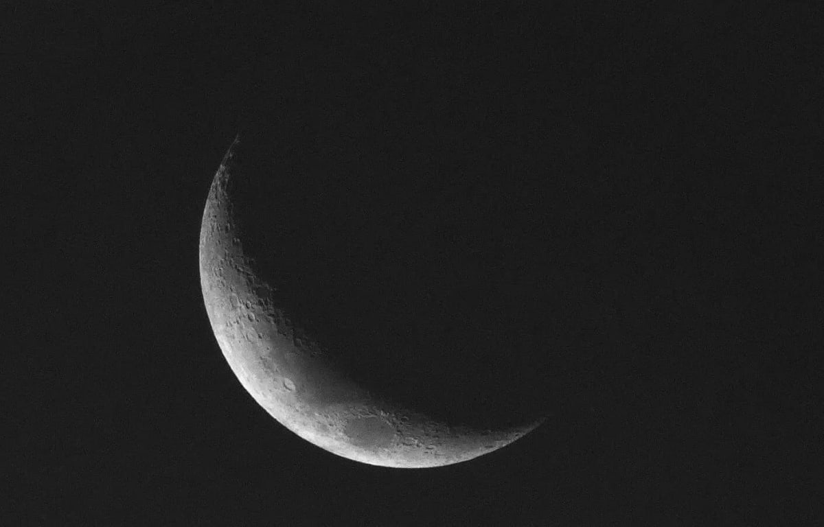 Luna en fase nueva con un fino borde iluminado visible en el cielo nocturno.