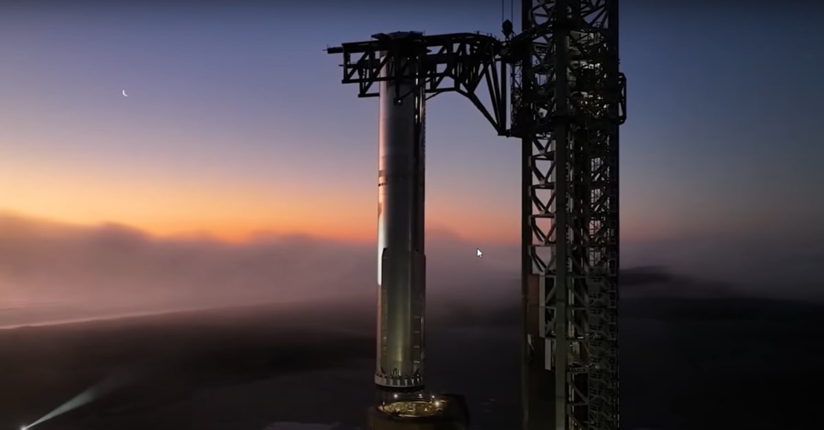 El cohete Starship de SpaceX en posición vertical sobre la plataforma de lanzamiento durante el amanecer.