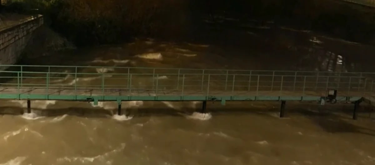Imagen del río Manzanares en Madrid con un caudal desbordado, cubriendo parcialmente una pasarela peatonal