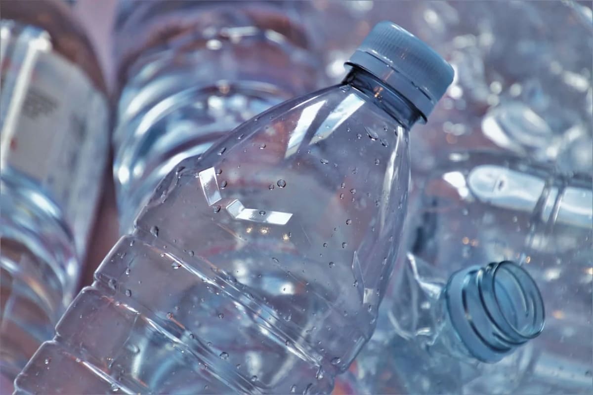 Primer plano de botellas de plástico transparentes acumuladas, con gotas de agua
