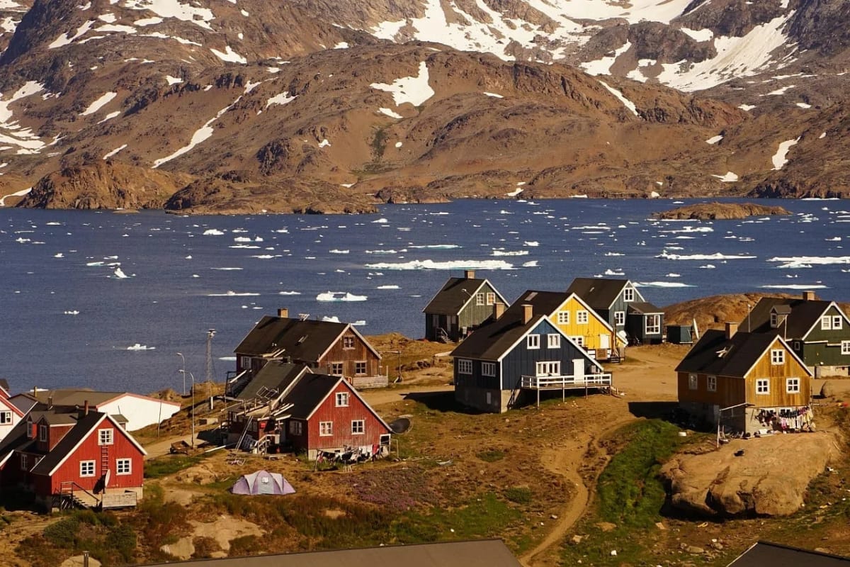 Vista de Tasiilaq, un asentamiento en la costa este de Groenlandia, en medio de un paisaje ártico con hielo flotante y viviendas coloridas.