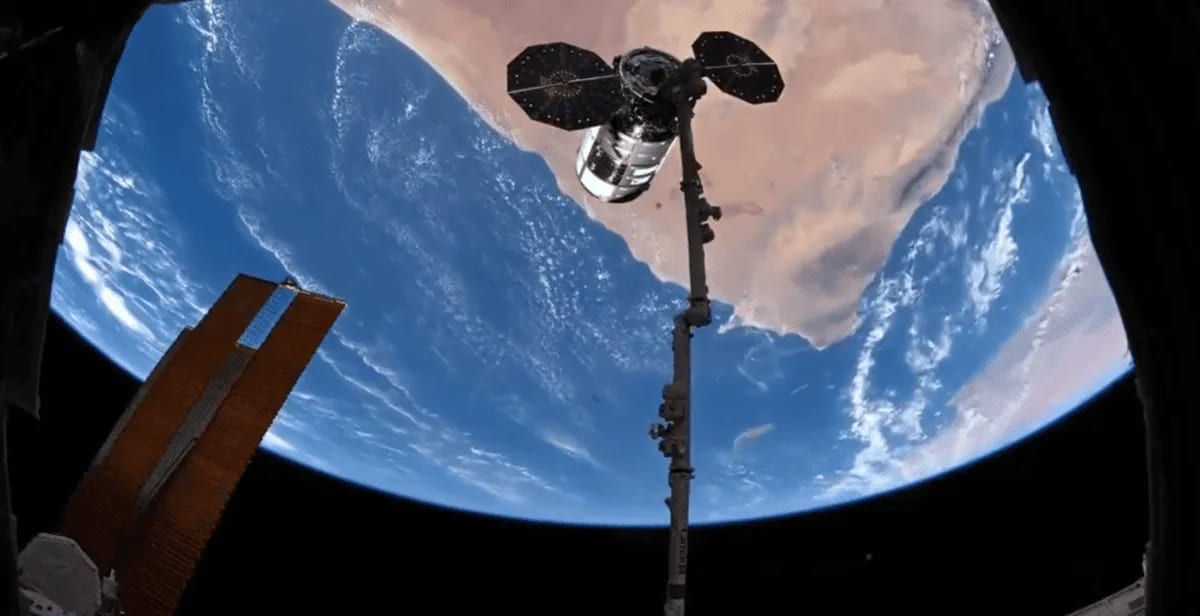 El vehículo Cygnus acoplado al brazo robótico Canadarm2 antes de su desacoplamiento desde la Estación Espacial Internacional, con la Tierra de fondo