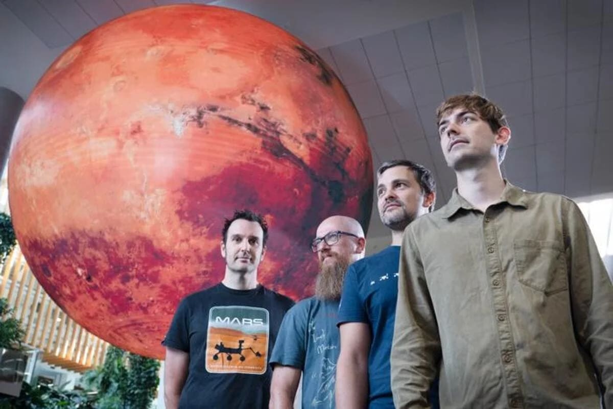 Miembros del equipo de investigación de QUT trabajando en el estudio sobre Marte, junto a un modelo del planeta.