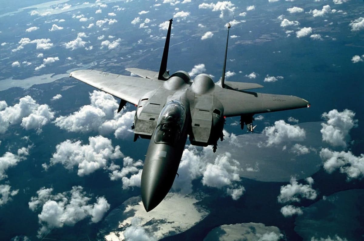 Avión de combate volando a gran altitud sobre formaciones nubosas