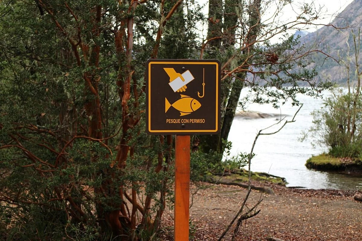 Cartel de pesca con permiso en zona natural junto a un lago
