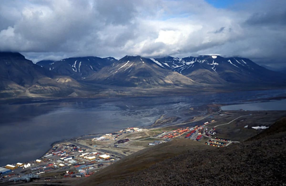Vista panorámica de Longyearbyen, con casas y montañas nevadas al fondo bajo un cielo nublado