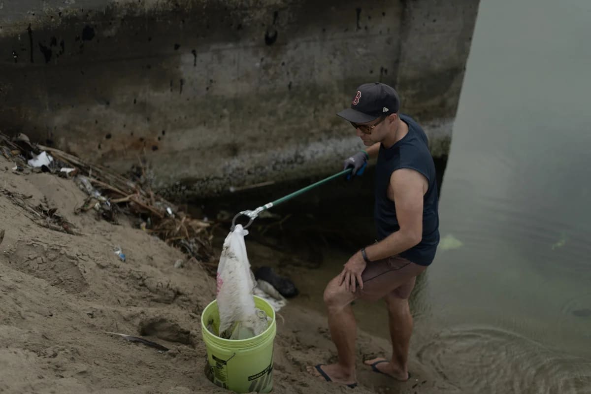 Voluntario retira una bolsa de plástico de la arena en Venice Beach
