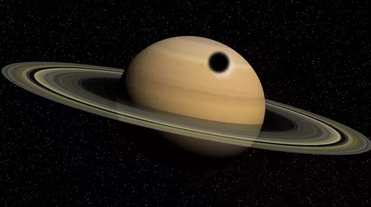 Saturno con la sombra de Titán proyectada como un círculo oscuro sobre su superficie
