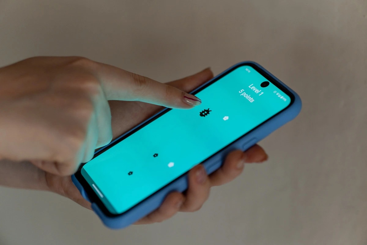 Persona jugando un videojuego sencillo en un teléfono móvil.