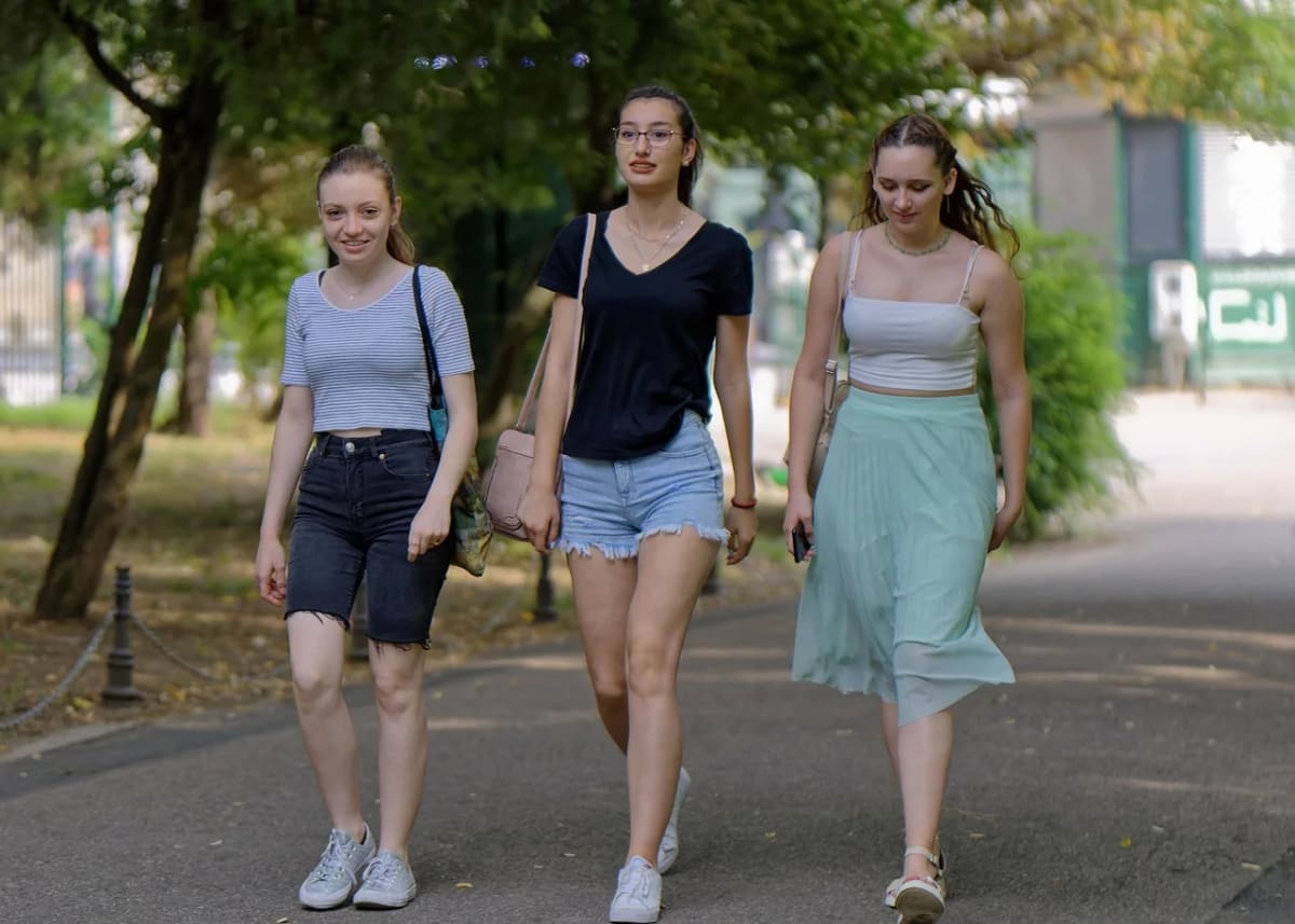 Tres jóvenes paseando por un parque, caminando juntas en un ambiente relajado y veraniego