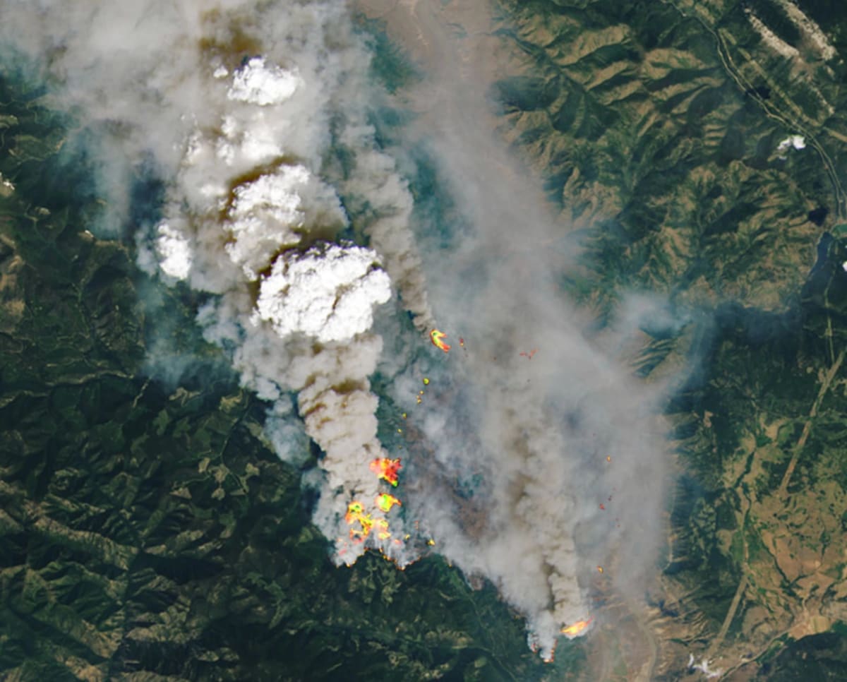 Incendio forestal en Columbia Británica visto desde el satélite Landsat 8, con pirocumulonimbos y humo sobre el paisaje
