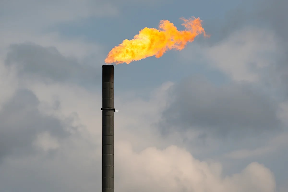 Chimenea industrial de quema de gas emitiendo una llama intensa