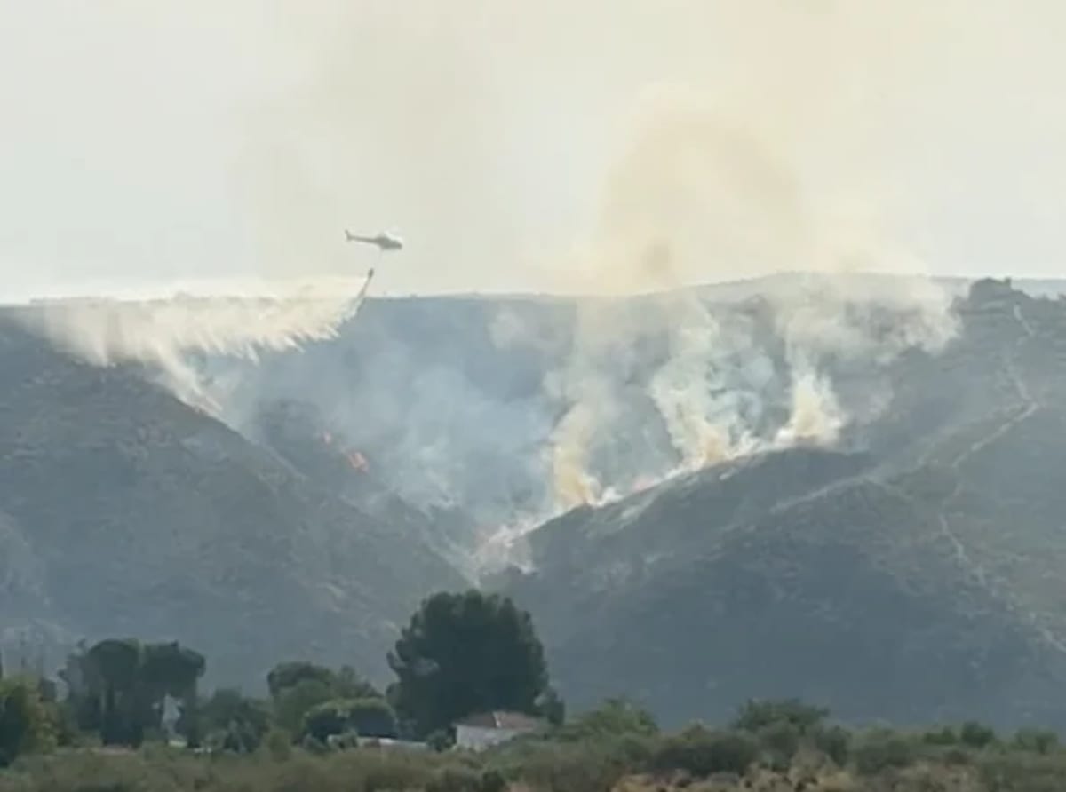 Helicóptero realizando descarga de agua sobre incendio forestal en las colinas de Aranjuez