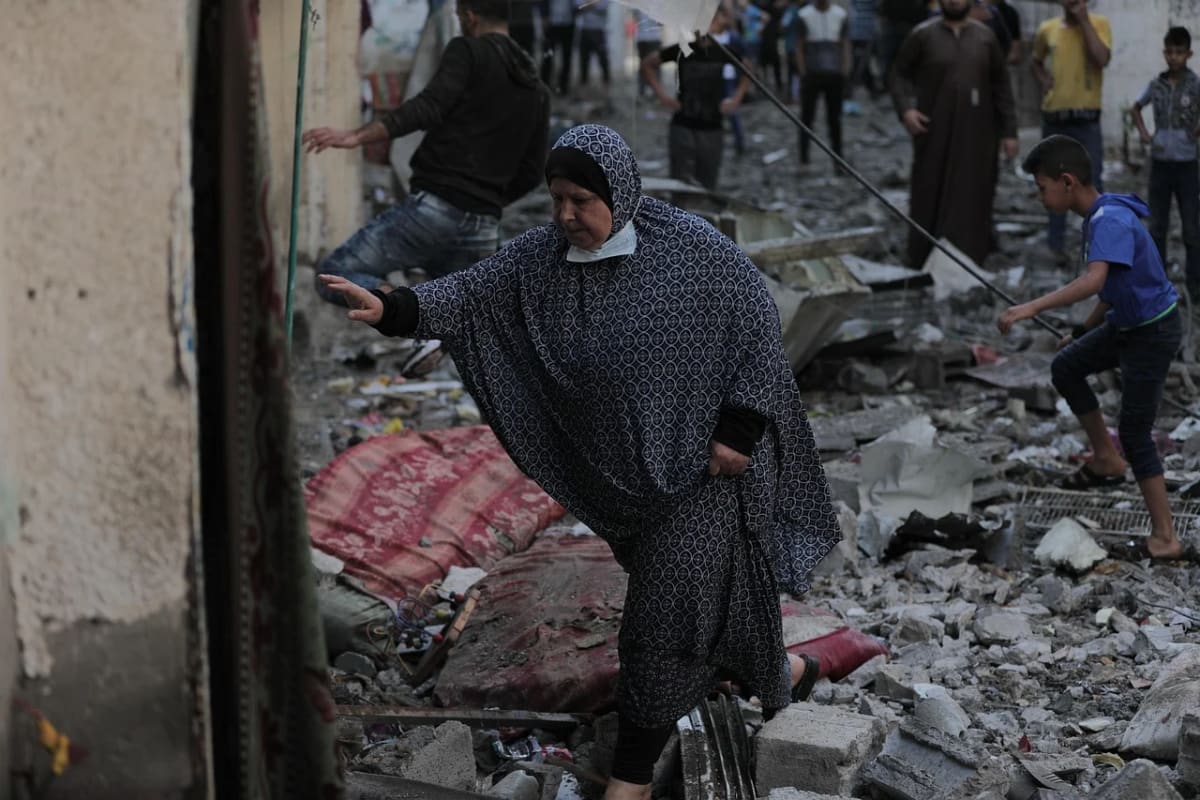 Mujer caminando entre escombros tras un bombardeo en Gaza