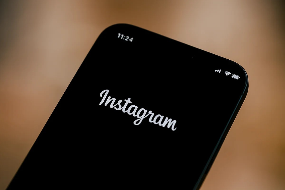 Teléfono inteligente con la aplicación Instagram en pantalla, fondo negro y vista horizontal