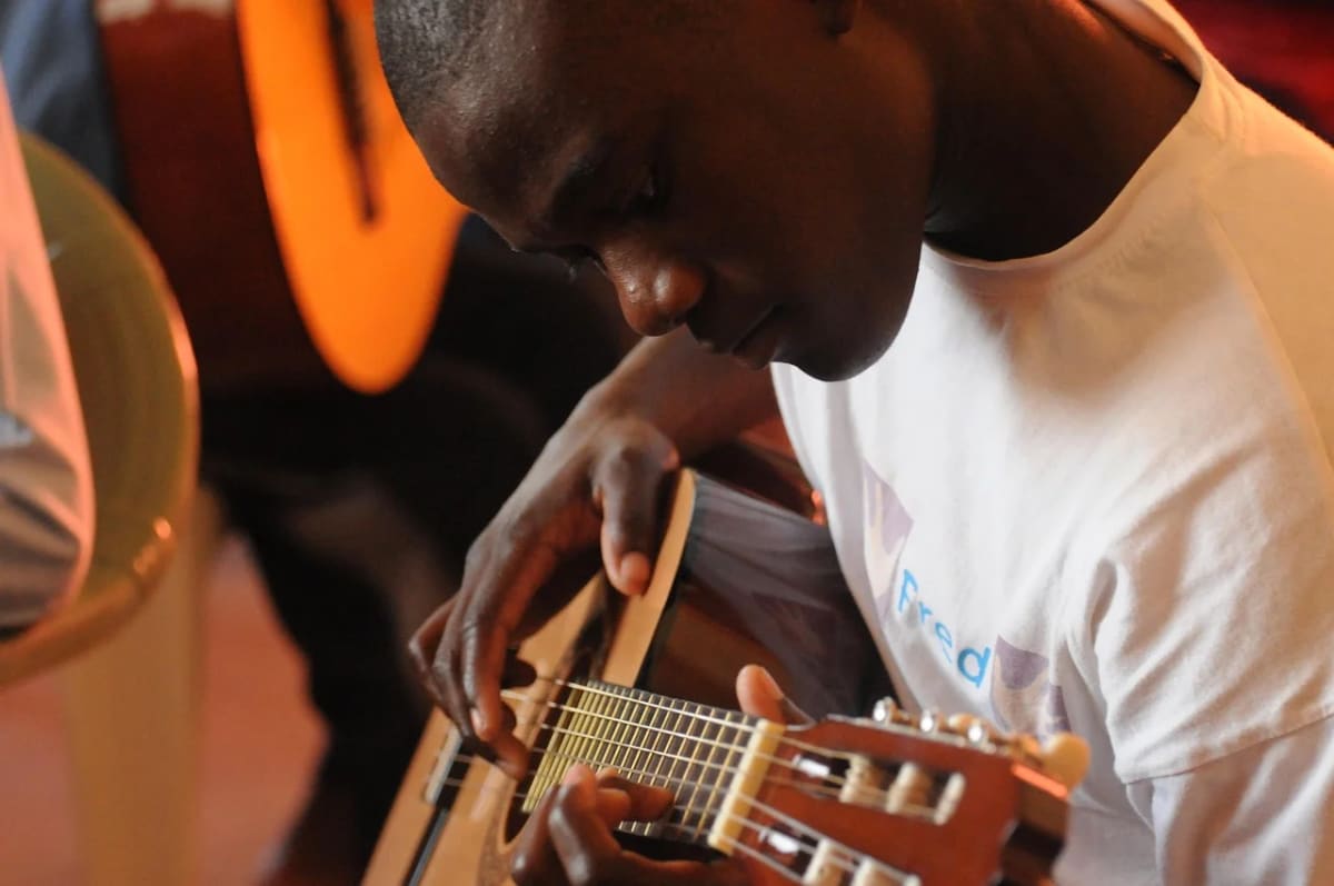 Joven tocando guitarra en una clase de música comunitaria