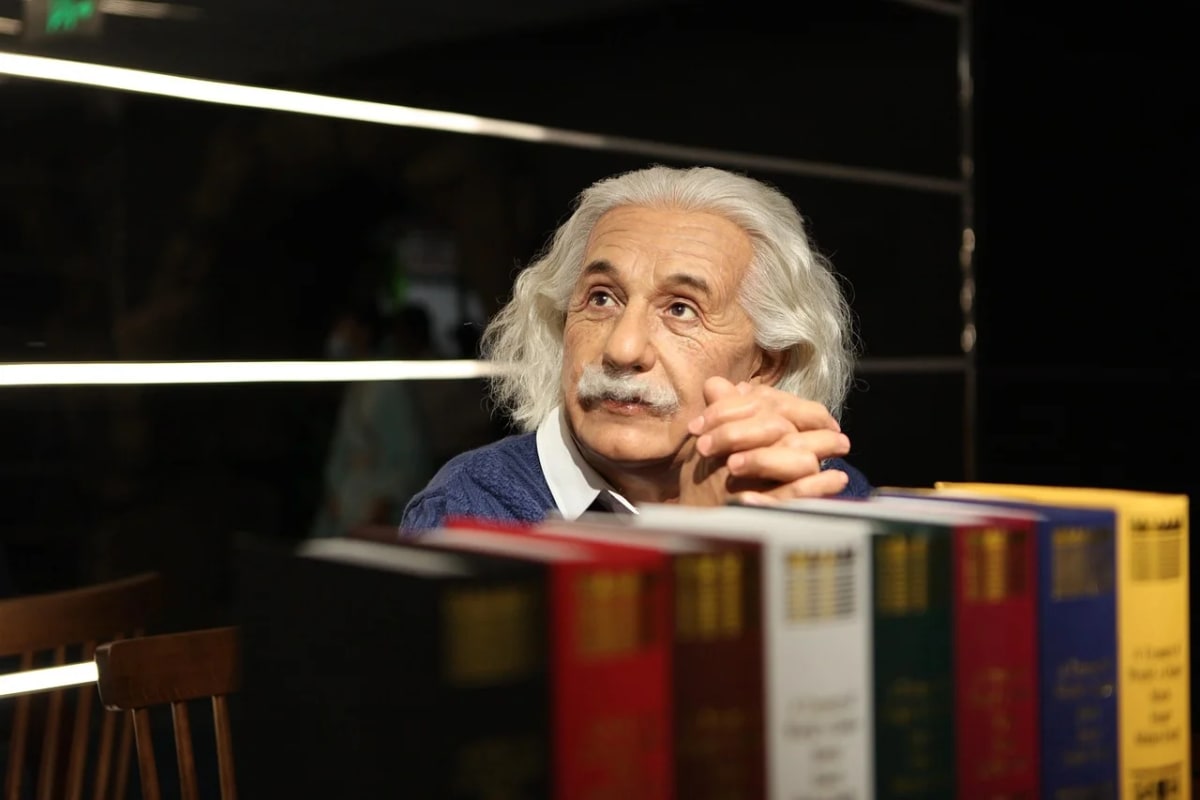 Figura de Albert Einstein en un museo sentado frente a libros