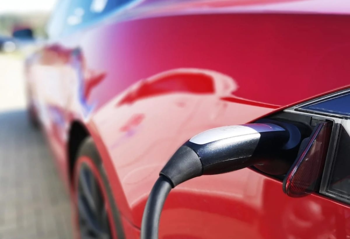 Auto eléctrico de color rojo conectado a un cargador en una estación de carga