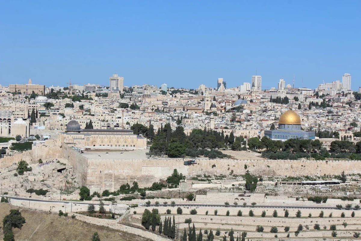 Vista panorámica de Jerusalén con la Cúpula de la Roca en primer plano y edificios modernos al fondo bajo un cielo despejado