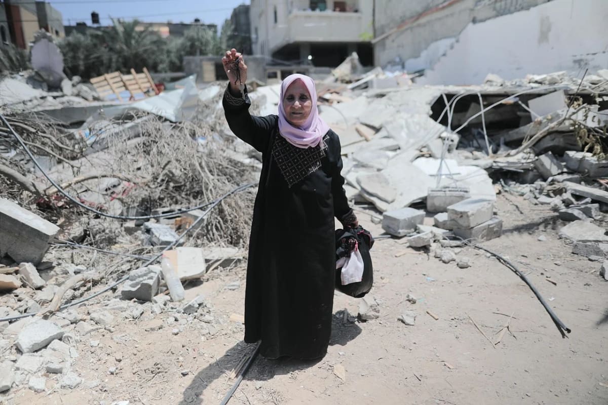 Mujer en Gaza sostiene llaves entre los escombros de una vivienda destruida tras los bombardeos