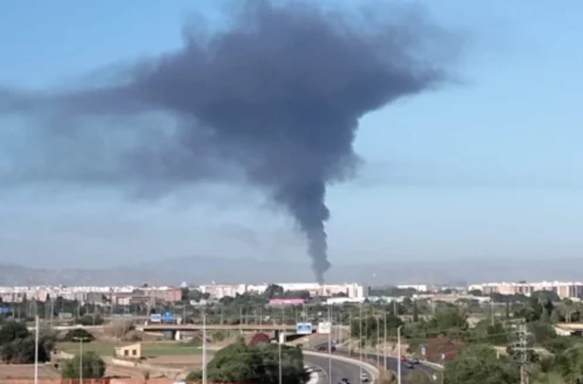 Gran columna de humo negro elevándose desde un incendio en un desguace de Quart de Poblet, visible en el horizonte de València