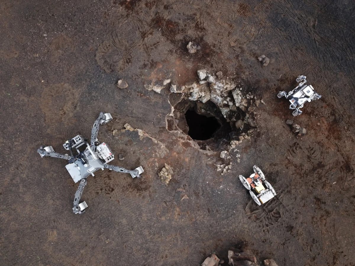 Tres robots del Laboratorio de Robótica Espacial de la Universidad de Málaga realizan pruebas en un terreno volcánico de Lanzarote frente a un tubo de lava