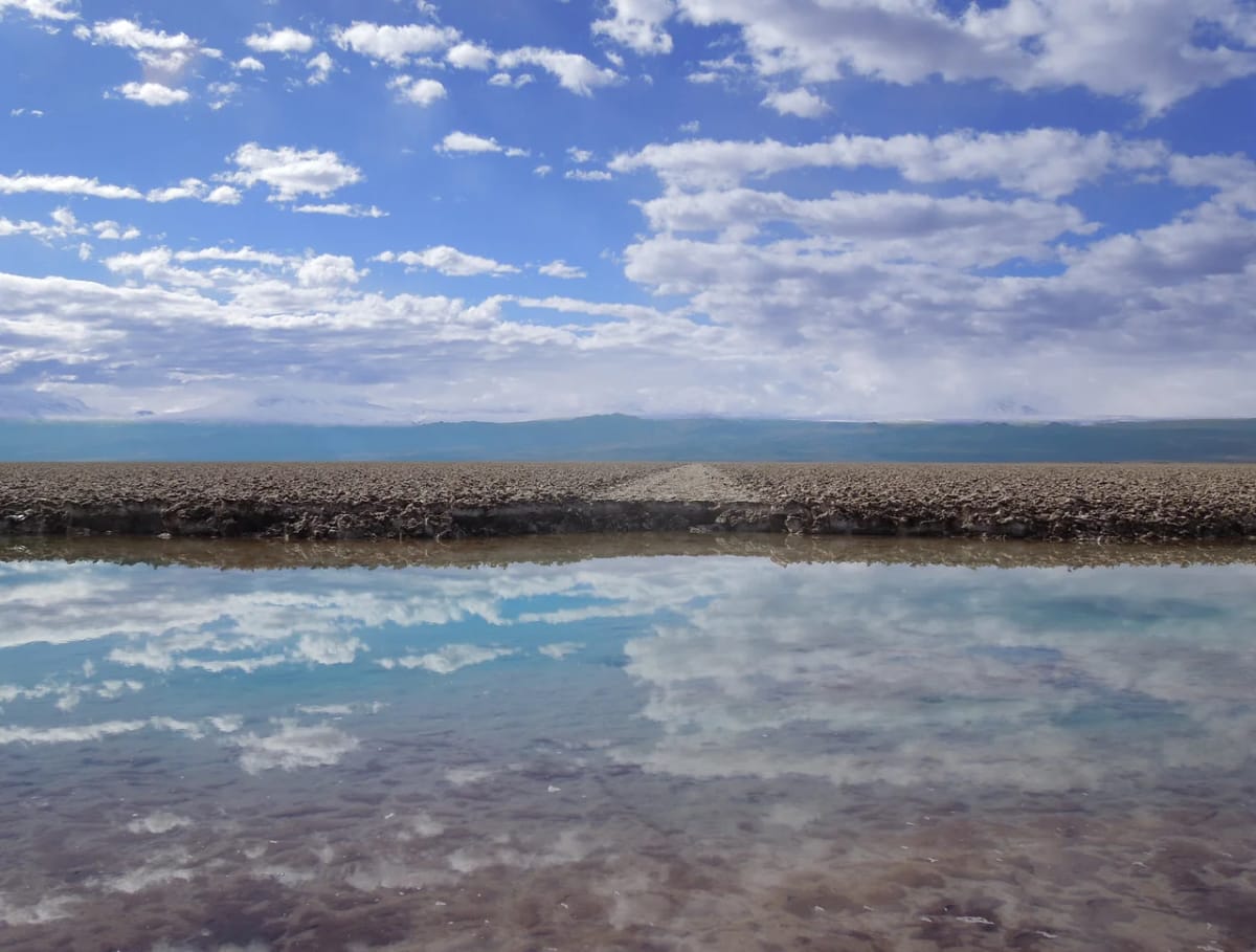 Paisaje de un salar andino con cielo parcialmente nublado reflejado en aguas superficiales