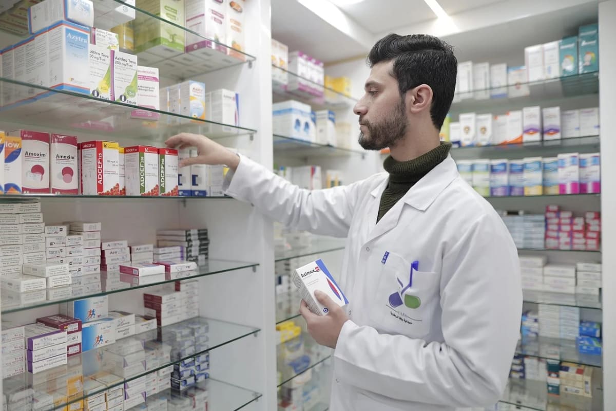 Farmacéutico organizando medicamentos en los estantes de una farmacia moderna