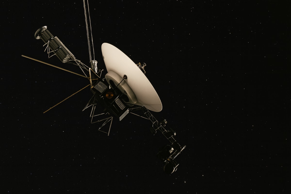 Ilustración artística de la nave espacial Voyager 1 viajando por el espacio interestelar con su antena de gran tamaño orientada hacia la Tierra