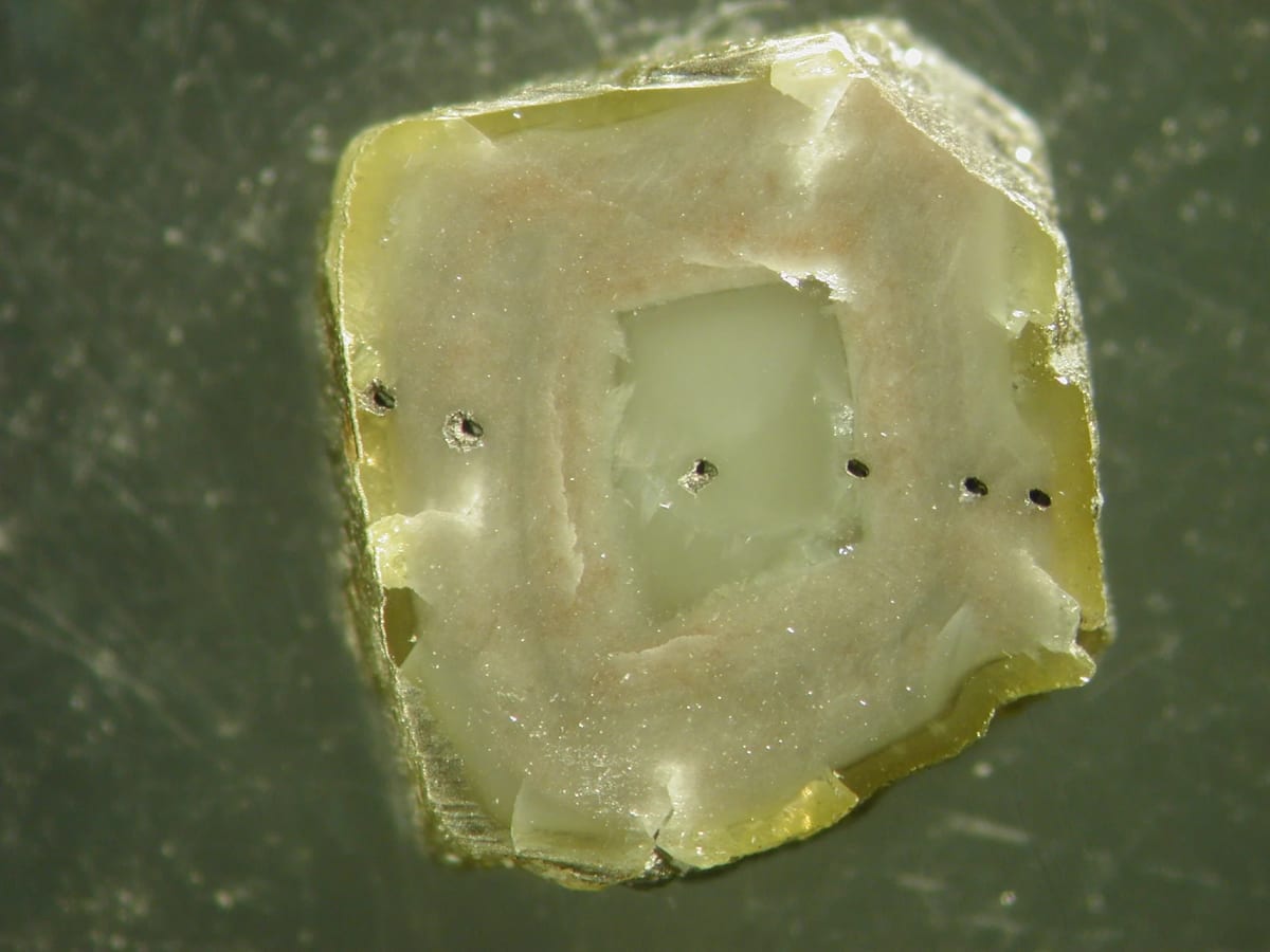 Corte de diamante sudafricano con zonas ricas en inclusiones y marcas de ablación láser de un muestreo microanalítico.