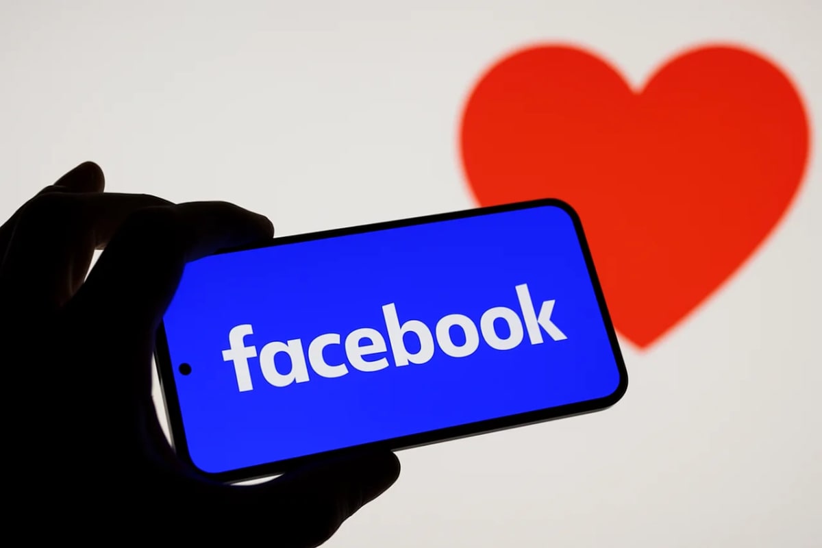 Un teléfono con la aplicación de Facebook en pantalla frente a un corazón rojo