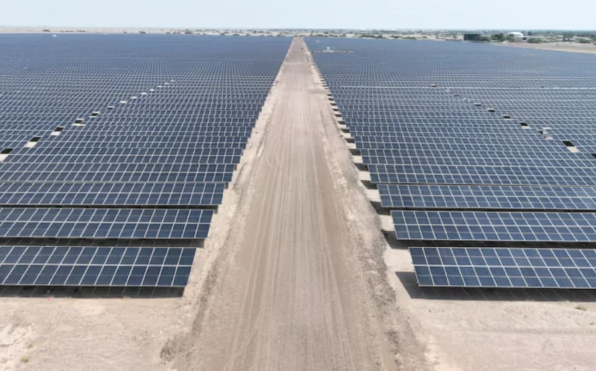 Vista aérea de la planta solar de Adén con cientos de paneles fotovoltaicos alineados en el desierto y un camino central de tierra