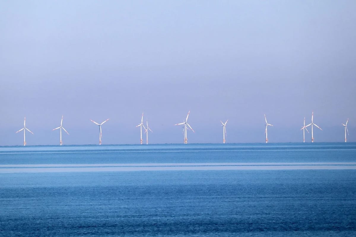 Parque eólico marino con aerogeneradores en el horizonte sobre aguas tranquilas