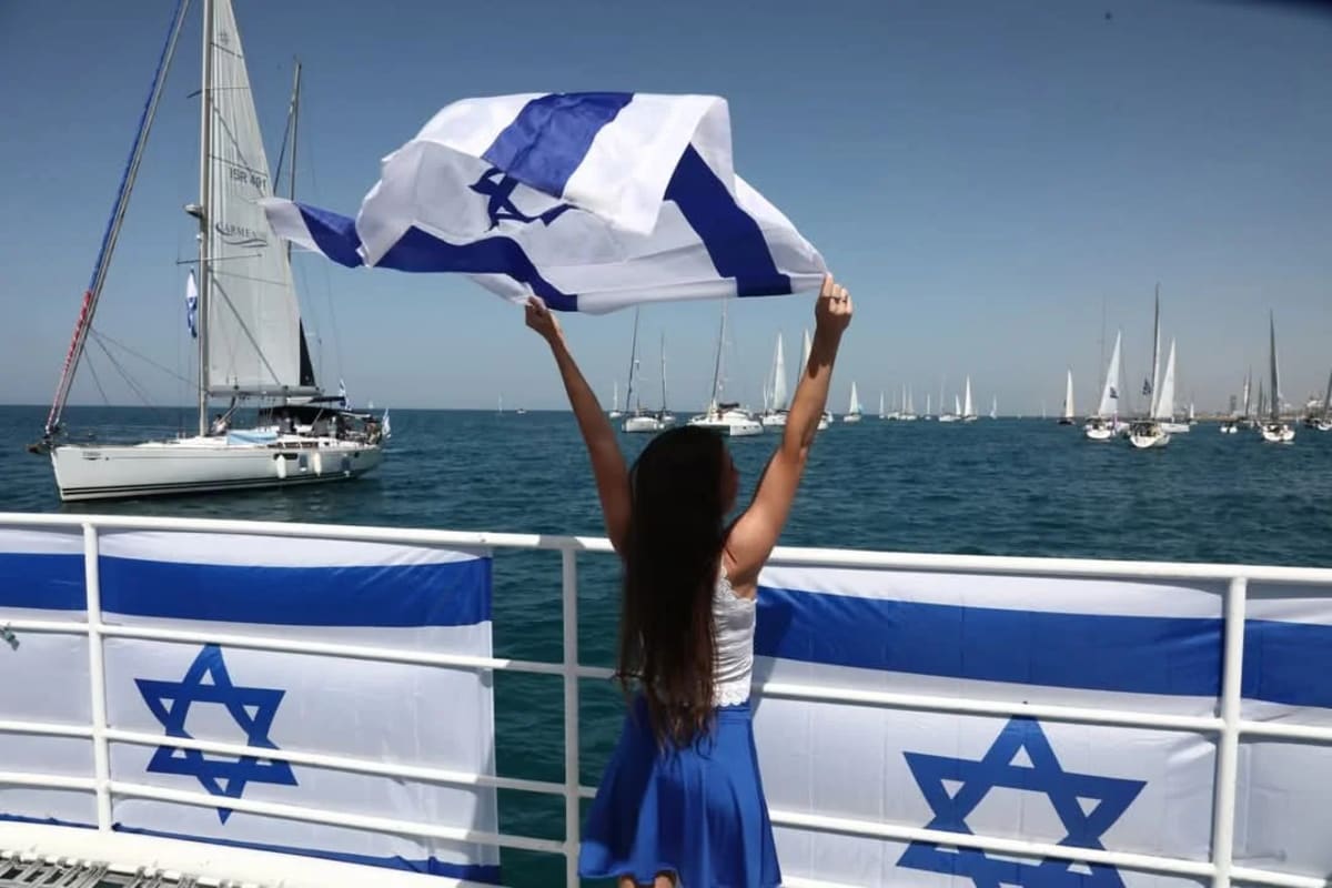 Joven ondea la bandera de Israel frente al mar durante una ceremonia conmemorativa del 7 de octubre