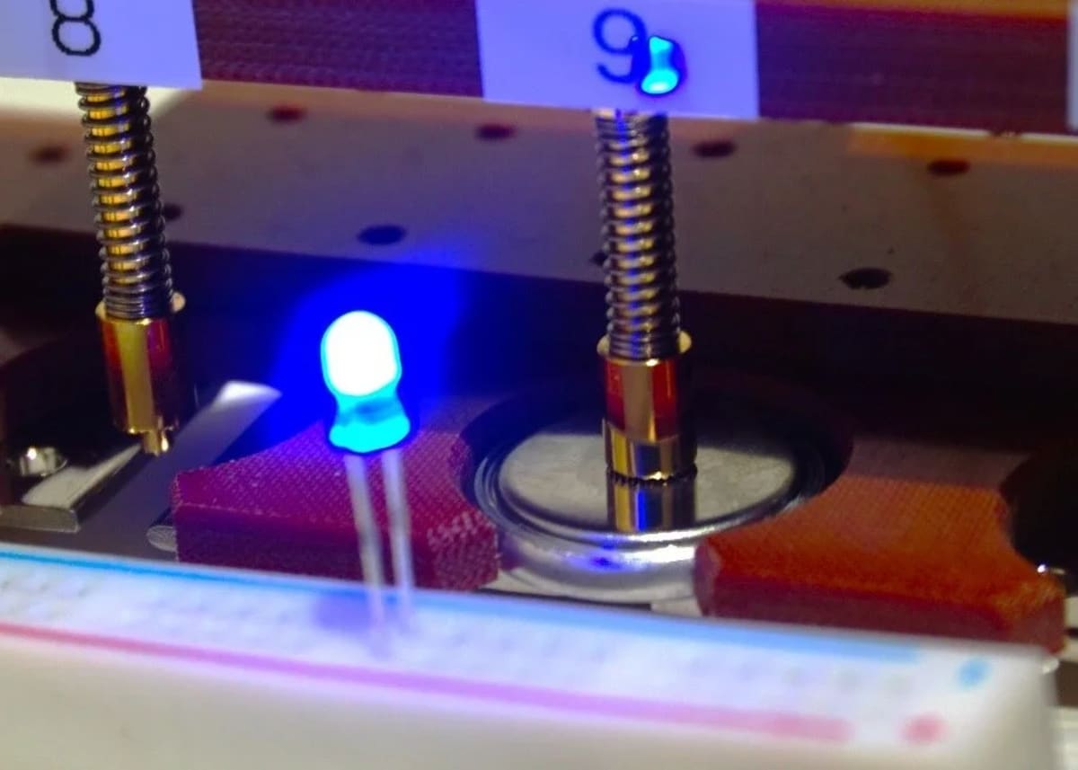 Prototipo de batería de botón de magnesio con cátodo de óxido amorfo encendiendo un LED azul