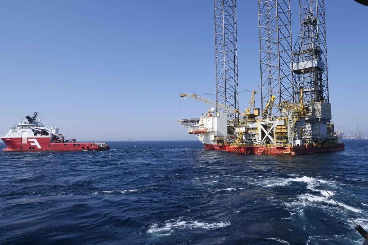 Plataforma petrolera en alta mar con un barco de apoyo rojo