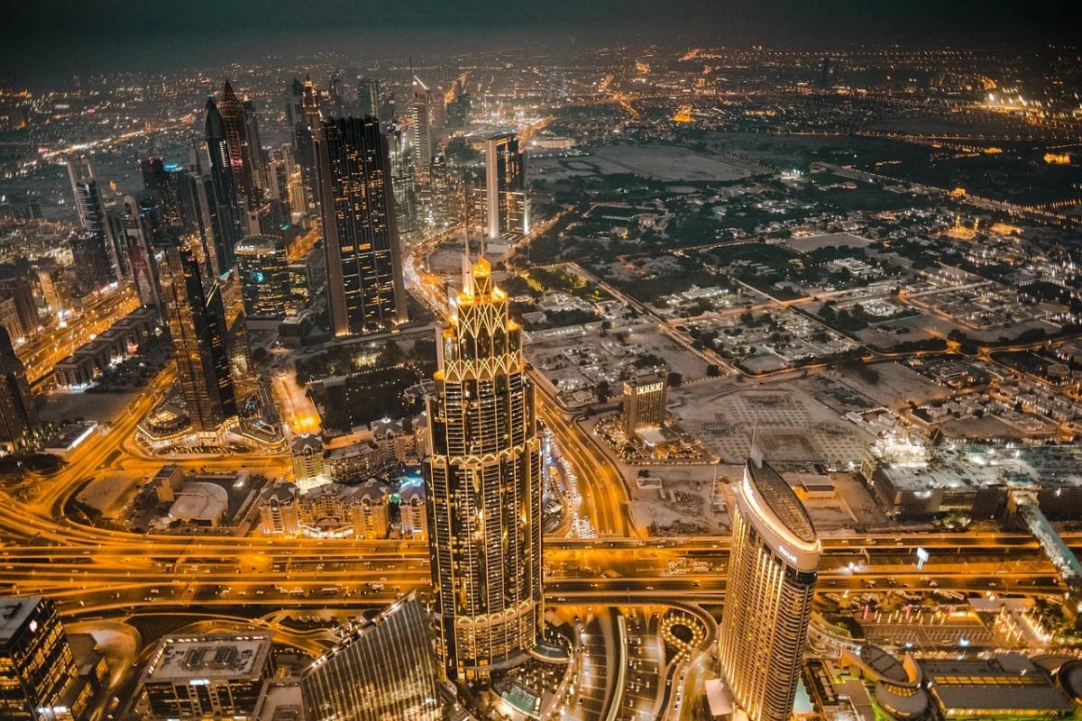 Vista aérea nocturna del centro de Dubái con rascacielos iluminados y autopistas