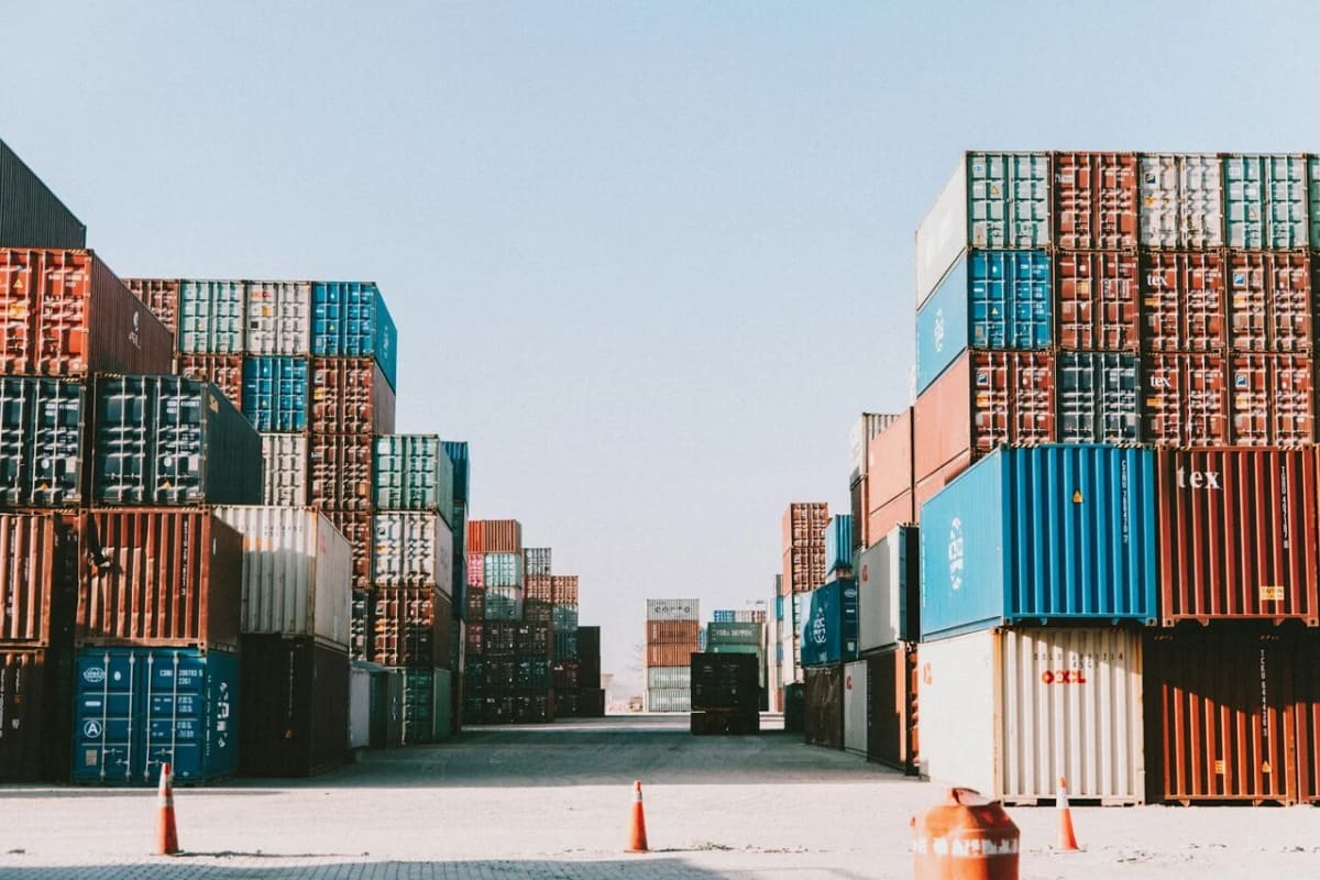 Filas de contenedores apilados en un puerto o zona industrial bajo un cielo despejado