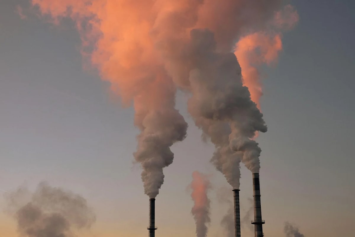 Chimeneas industriales emitiendo columnas de humo al atardecer